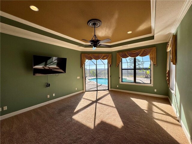 carpeted empty room featuring a raised ceiling, ceiling fan, and ornamental molding