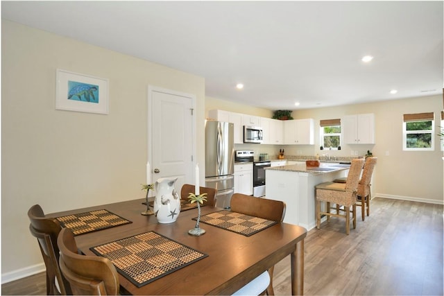 dining room featuring baseboards, wood finished floors, and recessed lighting