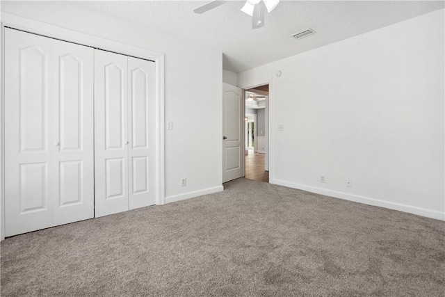 unfurnished bedroom featuring ceiling fan, carpet floors, a textured ceiling, and a closet