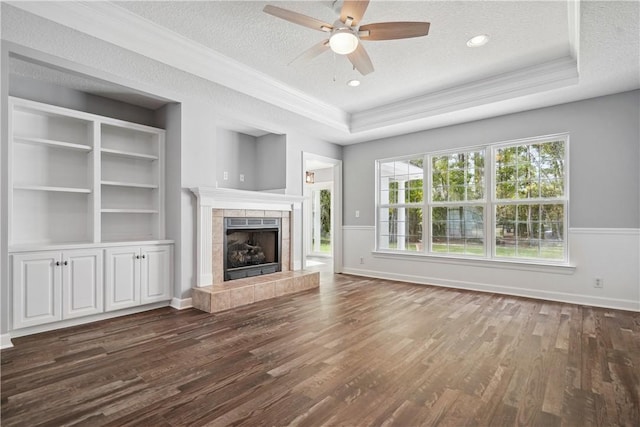 unfurnished living room with a raised ceiling, a tile fireplace, dark wood-type flooring, and a textured ceiling