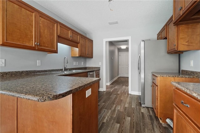 kitchen with sink, dark hardwood / wood-style floors, a textured ceiling, kitchen peninsula, and stainless steel appliances