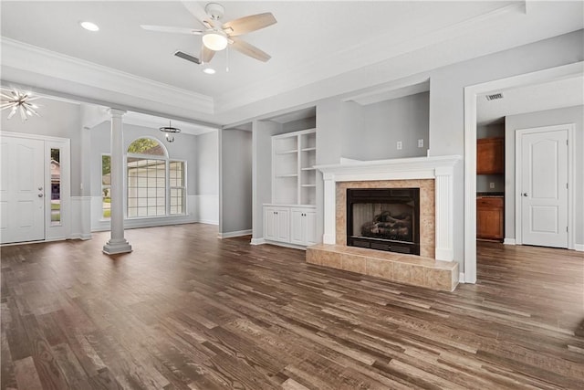 unfurnished living room featuring a tile fireplace, dark hardwood / wood-style flooring, ceiling fan with notable chandelier, and ornamental molding