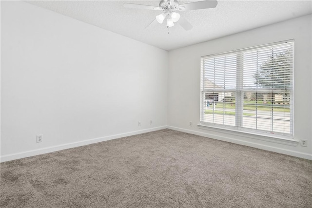 carpeted spare room with ceiling fan, a textured ceiling, and a wealth of natural light