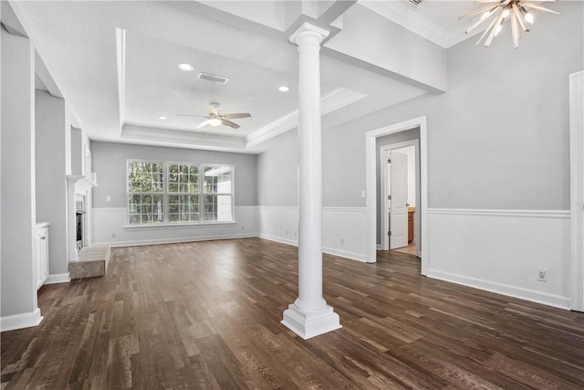 unfurnished living room with decorative columns, ornamental molding, ceiling fan with notable chandelier, a tray ceiling, and dark wood-type flooring