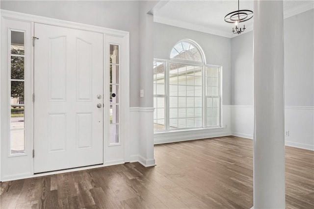 entryway with an inviting chandelier, dark hardwood / wood-style floors, and ornamental molding