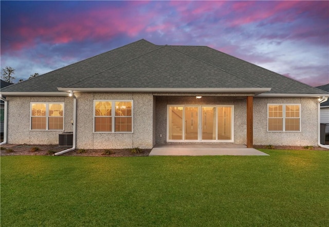 back house at dusk with a lawn, a patio area, and cooling unit