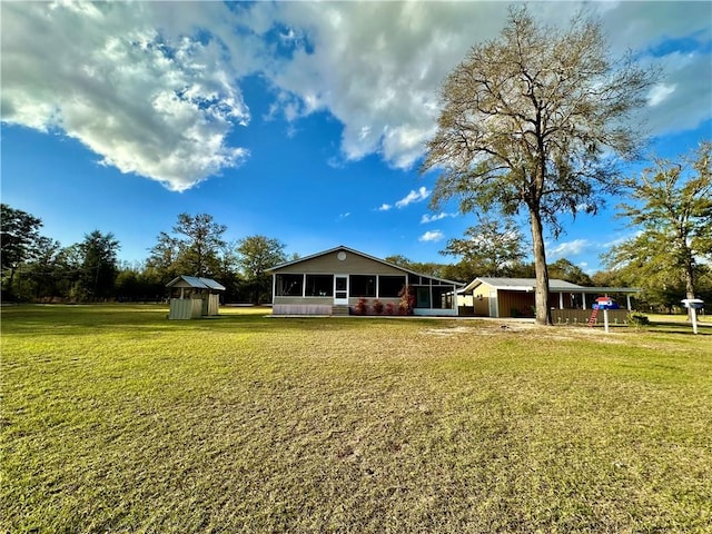 back of property featuring a shed, a sunroom, an outdoor structure, a garage, and a lawn