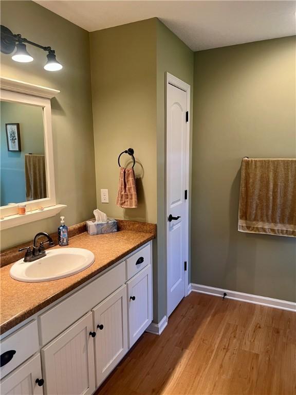 bathroom with vanity, wood finished floors, and baseboards