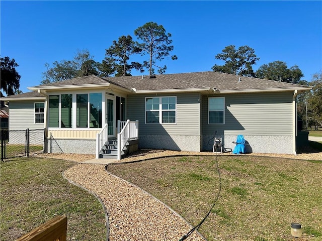 rear view of house featuring a gate, a yard, fence, and a sunroom