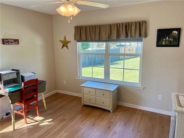 office space with baseboards, light wood-style flooring, and a ceiling fan