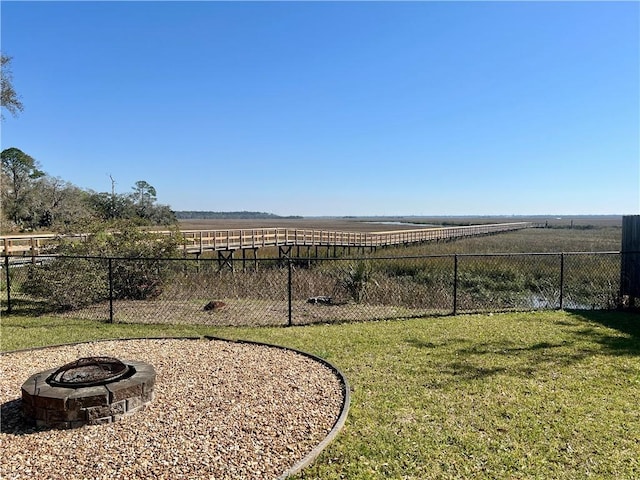 view of yard featuring a rural view, fence, and a fire pit