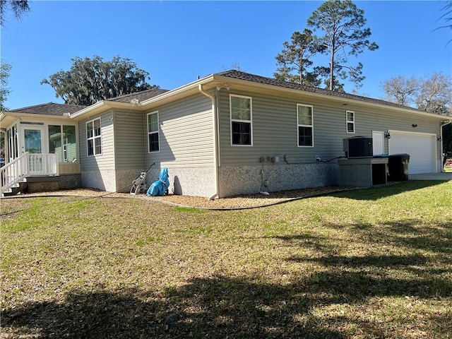 rear view of property with a yard, cooling unit, and an attached garage