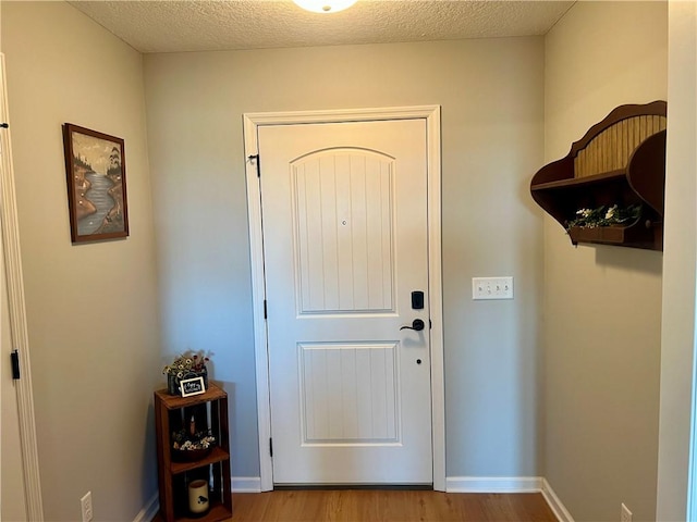 entryway featuring a textured ceiling, baseboards, and wood finished floors