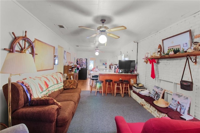 living room featuring ceiling fan and brick wall