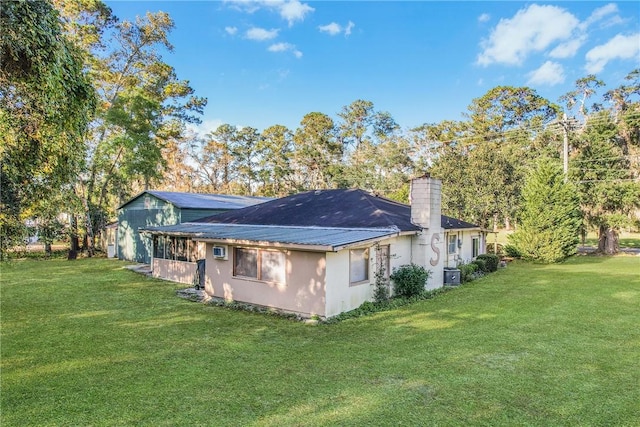 rear view of house with central AC and a lawn