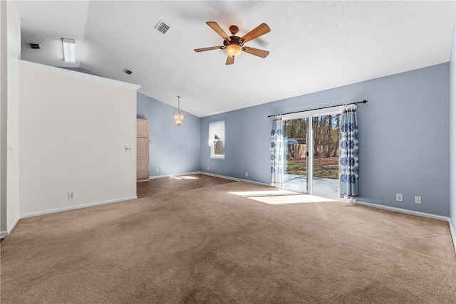 empty room featuring lofted ceiling, ceiling fan with notable chandelier, carpet, and a textured ceiling