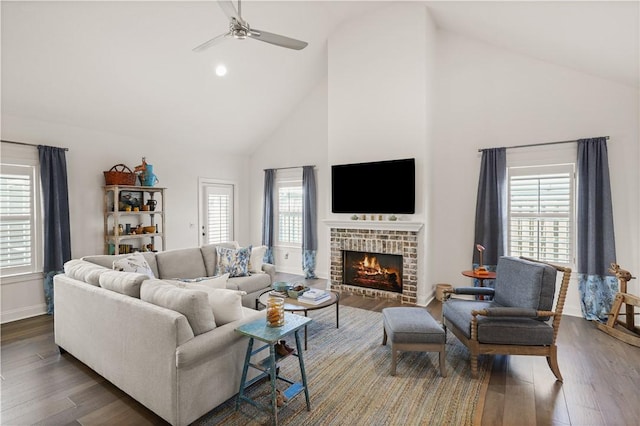 living room with a healthy amount of sunlight, a brick fireplace, high vaulted ceiling, and dark hardwood / wood-style floors