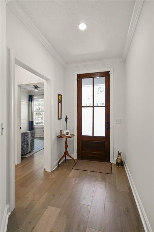 doorway with hardwood / wood-style flooring, ceiling fan, and ornamental molding