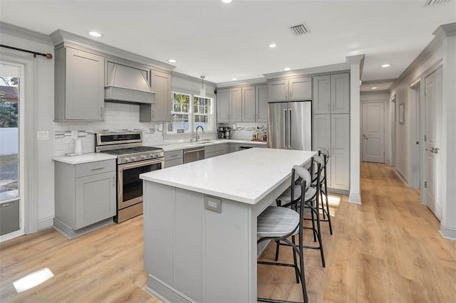 kitchen featuring a center island, hanging light fixtures, stainless steel appliances, a kitchen breakfast bar, and premium range hood