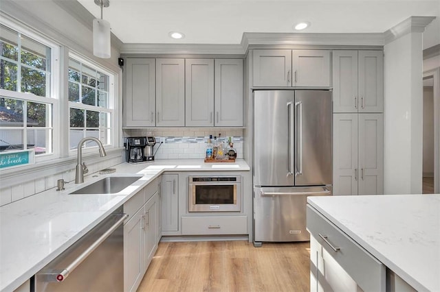 kitchen with sink, light hardwood / wood-style flooring, pendant lighting, decorative backsplash, and appliances with stainless steel finishes