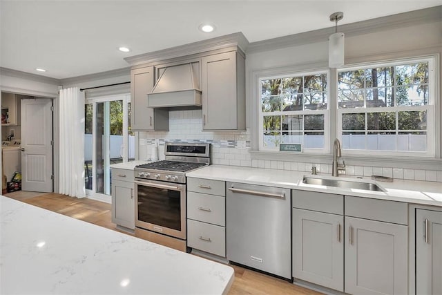 kitchen featuring sink, light hardwood / wood-style flooring, pendant lighting, appliances with stainless steel finishes, and custom exhaust hood