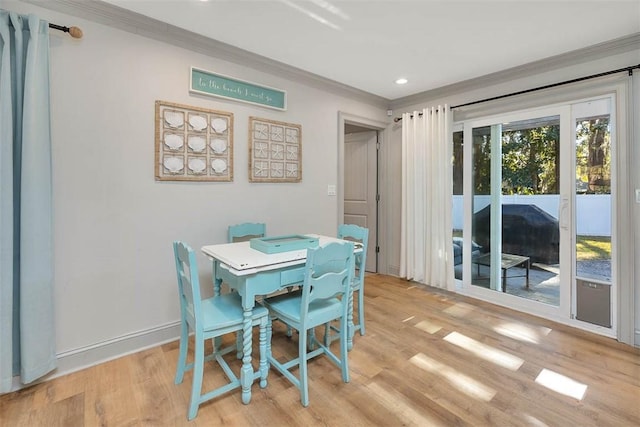 dining area with light wood-type flooring and ornamental molding