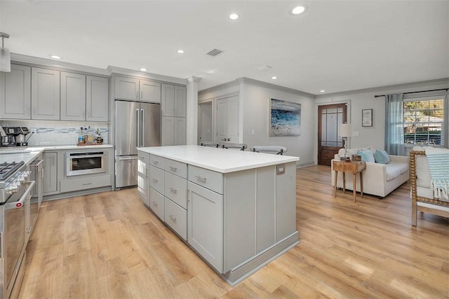 kitchen featuring backsplash, gray cabinets, a kitchen island, and high end appliances