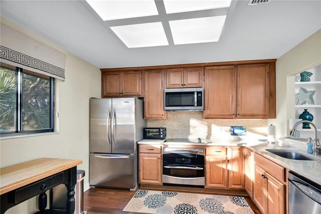 kitchen featuring a sink, backsplash, dark wood finished floors, stainless steel appliances, and light countertops