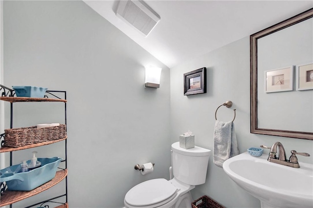 half bath featuring vaulted ceiling, toilet, visible vents, and a sink