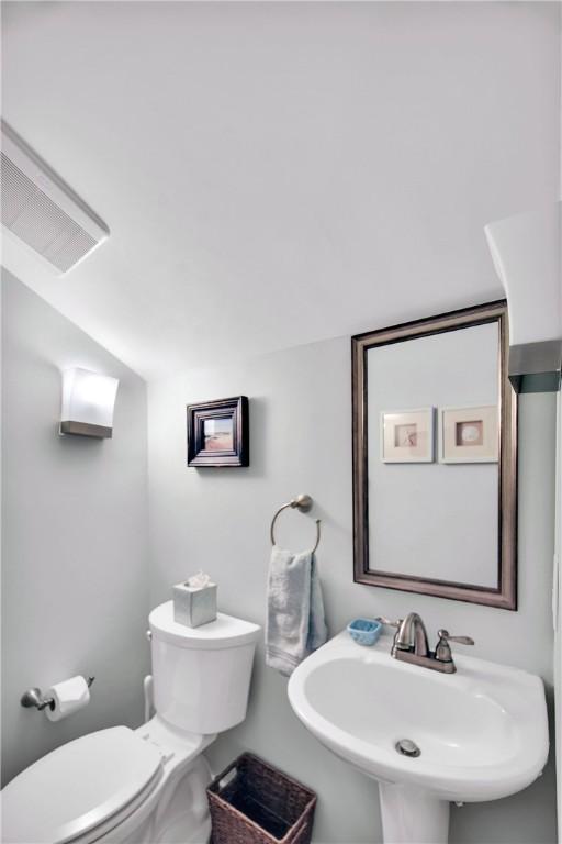 bathroom featuring vaulted ceiling, toilet, and a sink