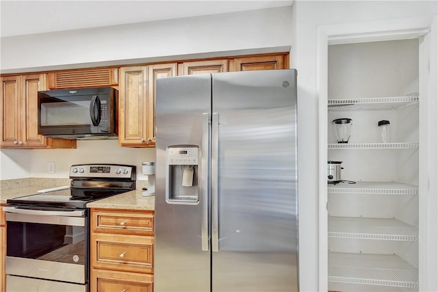 kitchen with appliances with stainless steel finishes and light stone counters