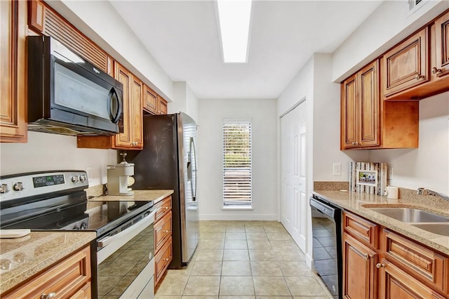 kitchen featuring light stone counters, sink, light tile patterned floors, and black appliances