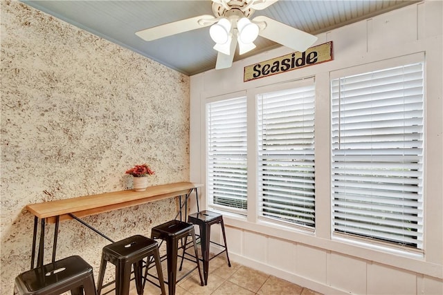 tiled dining area with ceiling fan and ornamental molding