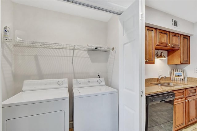 washroom featuring light tile patterned floors, washer and clothes dryer, and sink