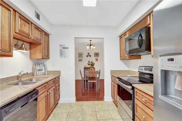 kitchen with light stone countertops, sink, black appliances, light tile patterned floors, and pendant lighting