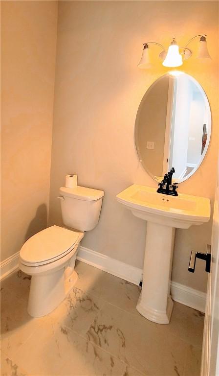 half bath featuring toilet, marble finish floor, and baseboards