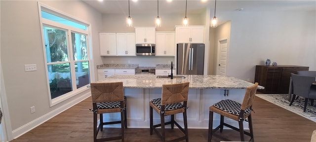 kitchen with white cabinets, dark wood finished floors, a breakfast bar, stainless steel appliances, and a sink