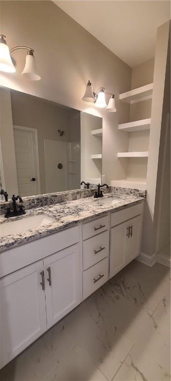 full bathroom with marble finish floor, double vanity, and a sink