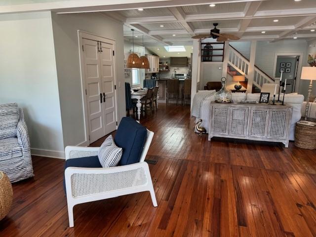 living room featuring dark hardwood / wood-style floors, coffered ceiling, and beamed ceiling