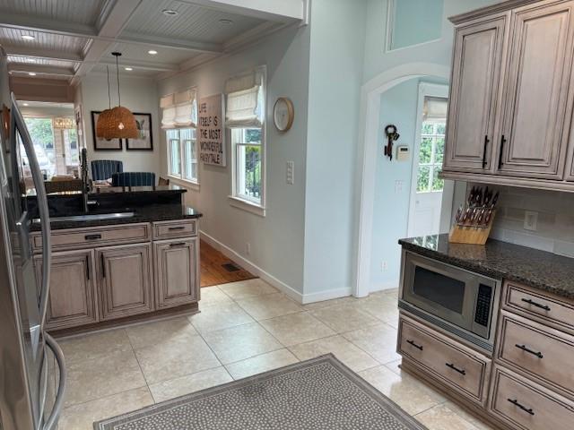 kitchen featuring a wealth of natural light, appliances with stainless steel finishes, dark stone countertops, and coffered ceiling