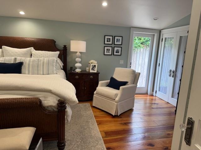 bedroom featuring access to exterior, wood-type flooring, lofted ceiling, and french doors