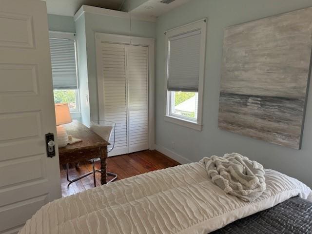 bedroom featuring a closet, multiple windows, and hardwood / wood-style flooring