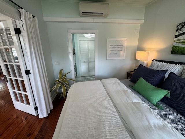 bedroom with dark hardwood / wood-style floors and a wall mounted air conditioner