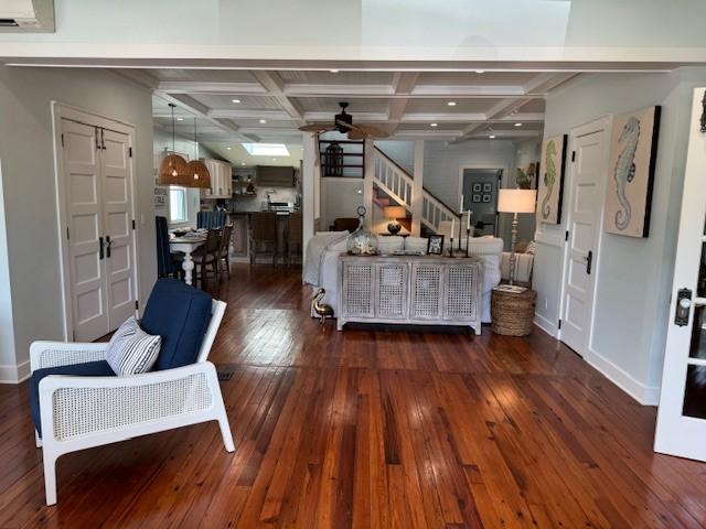 living room with dark hardwood / wood-style flooring, beamed ceiling, and coffered ceiling