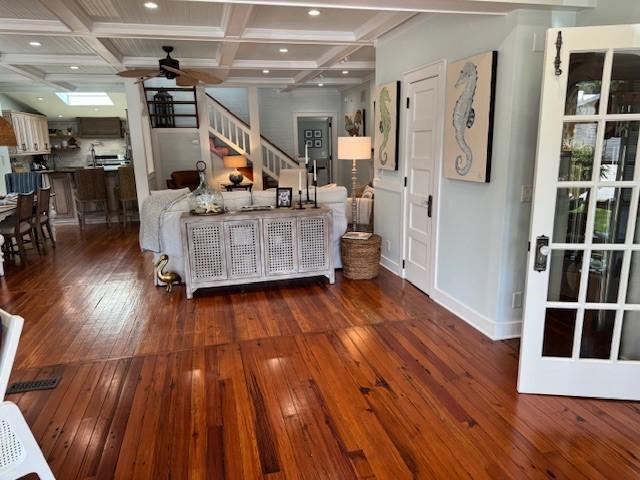 living room with dark hardwood / wood-style flooring, beam ceiling, and coffered ceiling