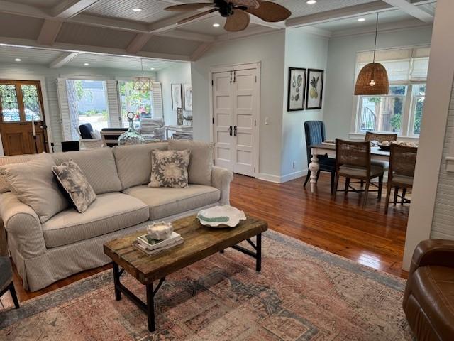 living room featuring ceiling fan, a healthy amount of sunlight, wood-type flooring, and beamed ceiling