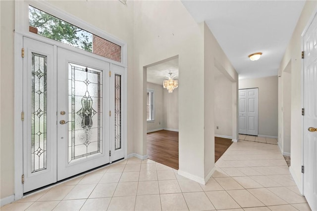 foyer entrance featuring light tile patterned floors, a notable chandelier, and a wealth of natural light