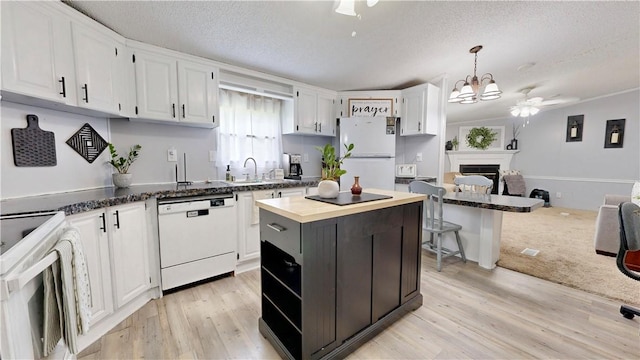 kitchen featuring a textured ceiling, wood counters, white cabinets, and white appliances