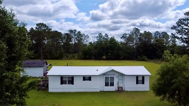 manufactured / mobile home with entry steps, metal roof, and a front yard