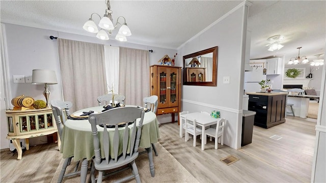 dining room with a textured ceiling, a chandelier, and light wood-style flooring